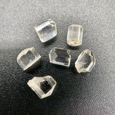 6-piece lot of short, fat, stubby Burmese phenakite crystals on black background. available at sanctuaryofstones.com