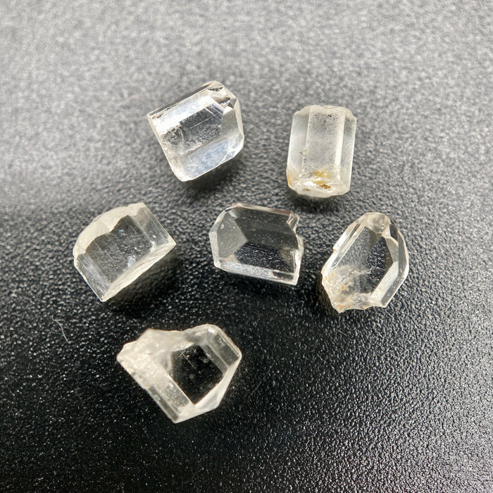 6-piece lot of short, fat, stubby Burmese phenakite crystals on black background. available at sanctuaryofstones.com