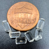 6-piece lot of Burmese phenakite hexagonal barrel crystals that are optically clear on black background next to one cent piece to show size. available at sanctuary of stones dot com | sanctuaryofstones.com