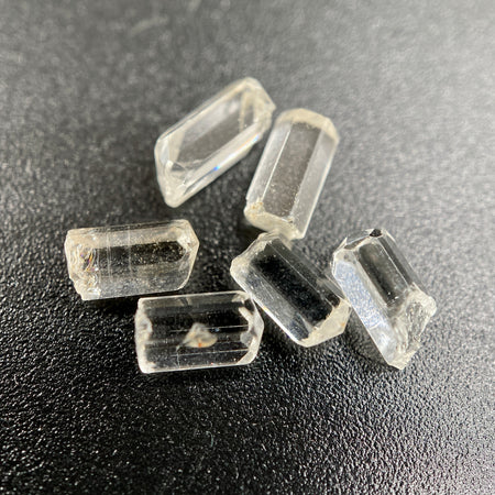 6-piece lot of Burmese phenakite hexagonal barrel crystals that are optically clear on black background available at sanctuary of stones dot com | sanctuaryofstones.com