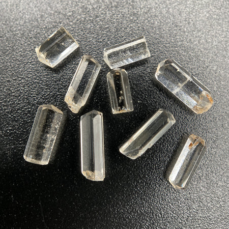 9-piece Burmese phenakite crystal lot on black background. Available at sanctuaryofstones.com