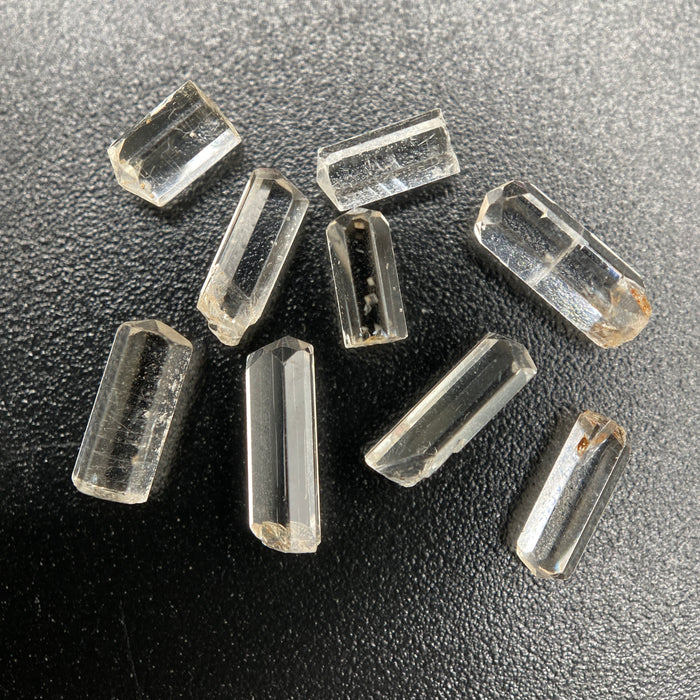 9-piece Burmese phenakite crystal lot on black background. Available at sanctuaryofstones.com