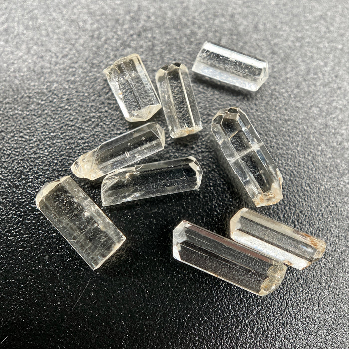 9-piece Burmese phenakite crystal lot on black background. Available at sanctuaryofstones.com