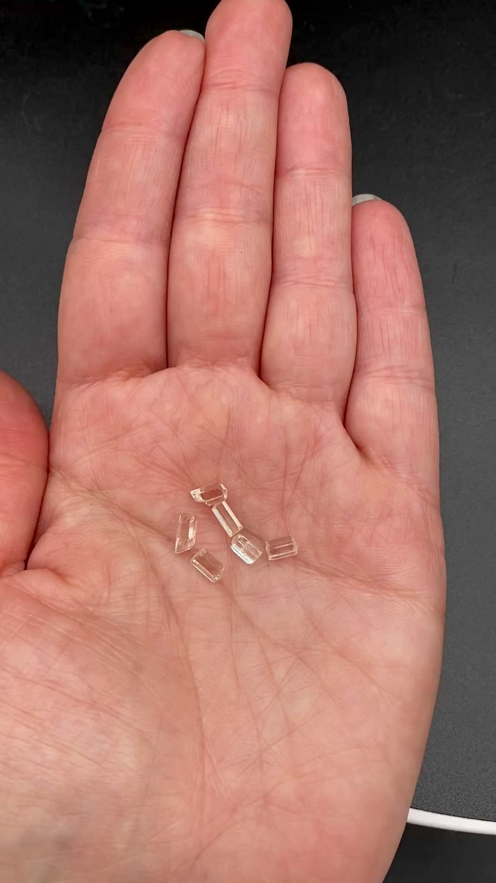 6-piece lot of Burmese phenakite hexagonal barrel crystals that are optically clear in hand to show size. available at sanctuary of stones dot com | sanctuaryofstones.com