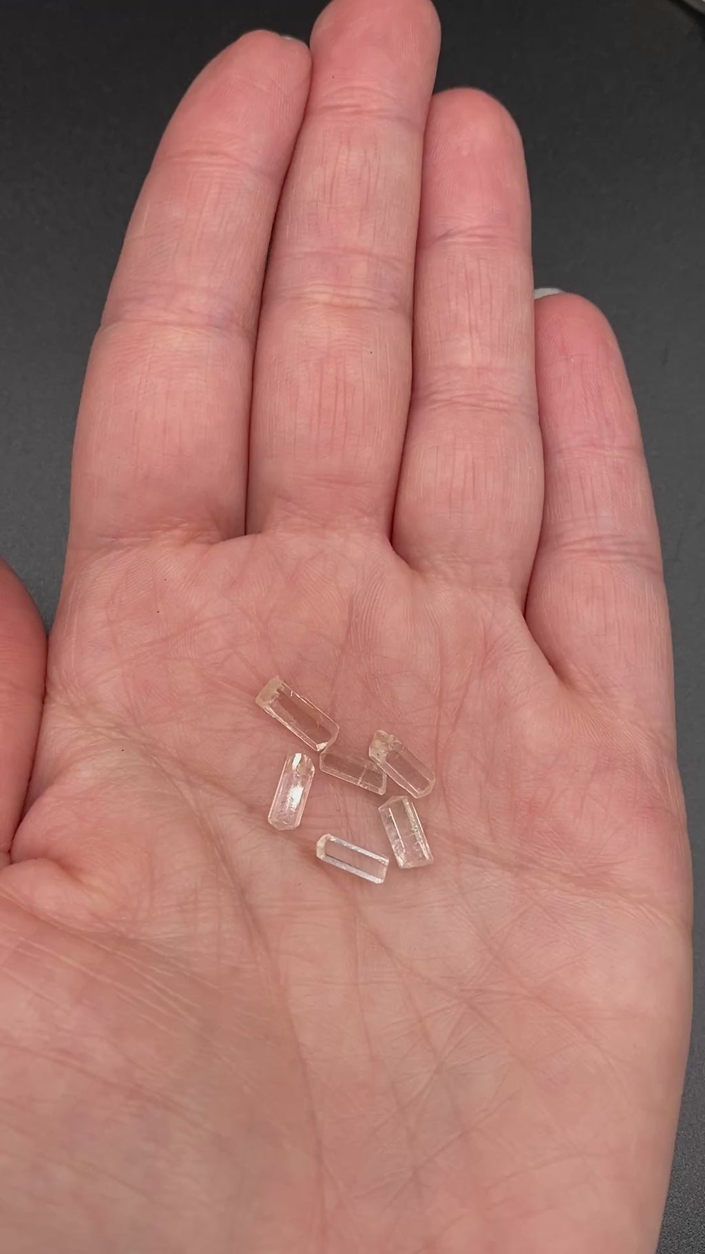 0.78 gram 6-piece lot of crystal clear Burmese phenakite crystals on a hand to show size. available at sanctuaryofstones.com