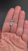 rare brazilian phenakite gemstone faceted oval shape in hand to show size. available at sanctuaryofstones.com