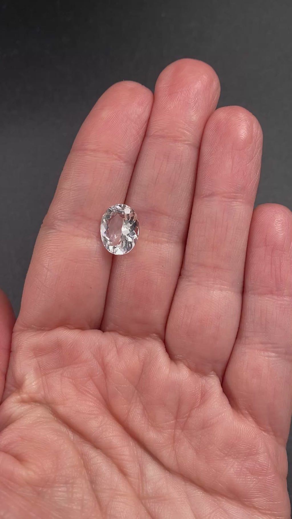 rare brazilian phenakite gemstone faceted oval shape in hand to show size. available at sanctuaryofstones.com