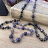 photo 1 of sanctuary vibrational jewelry's Harmonics of Light and Shadow hand-knotted beaded necklace with natural iolite rutilated gray moonstone and indigo gabbro